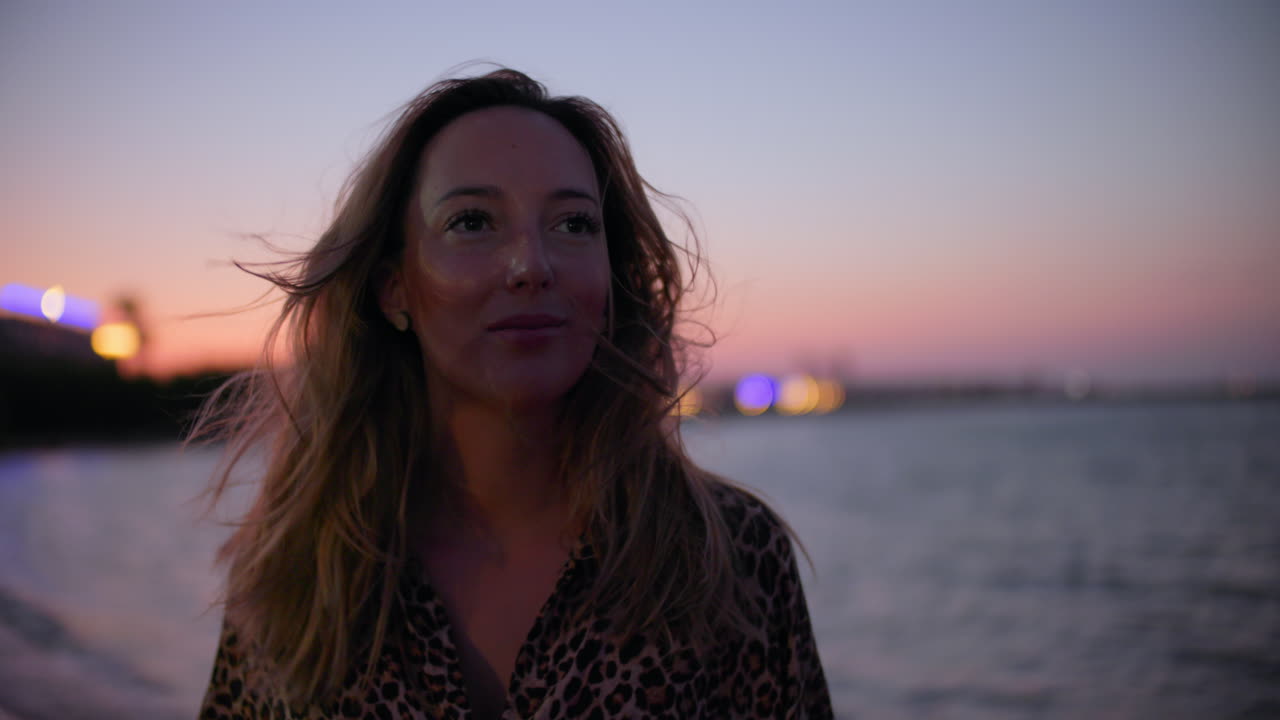 Close-up de uma linda jovem na praia ventosa ao pôr do sol.