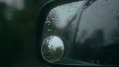 reflection in mirror dotted with raindrops of a country road in the uk