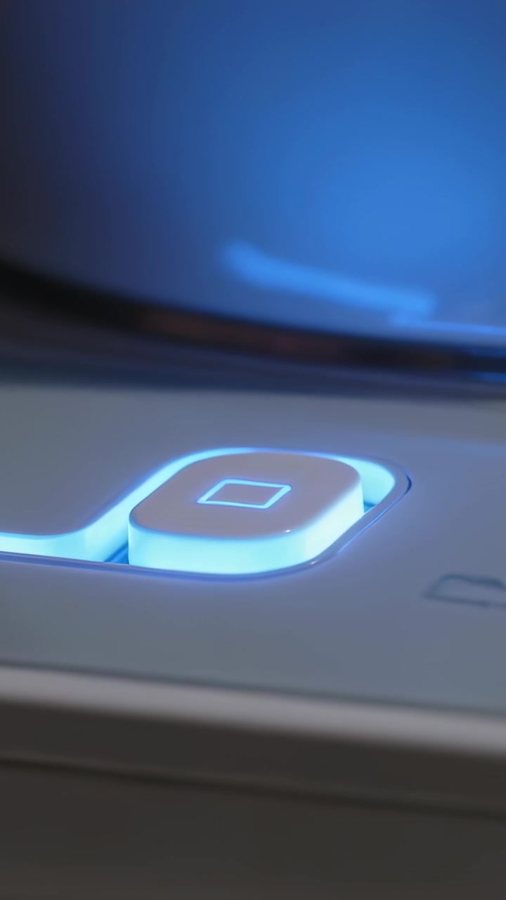 Vertical video: Pressing finger activating white button on pale panel under metal knob, blue glow