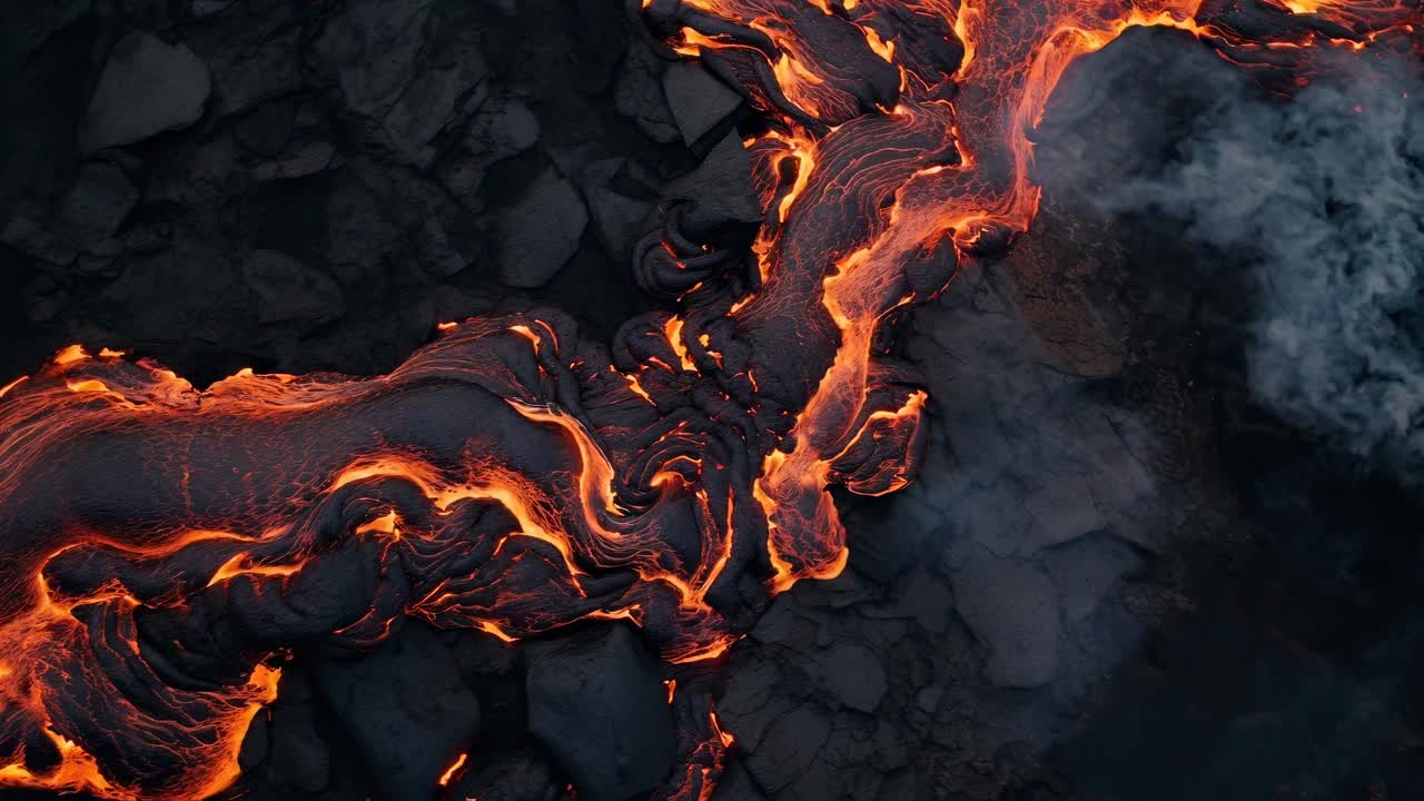 Vista aerea di lava che scorre su rocce scure, che cattura il movimento dinamico e i colori vivaci