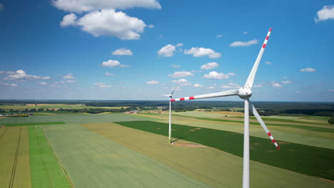 Aerial-Close-Up-of-Wind-Turbines-With-Rotating-Blades-on-Countryside-Green-Agricultural-Field