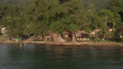 drone side trucking shot of empty tourist backpacker style bungalows on the sea in koh chang thailand, due to the effects of covid on travel and tourism