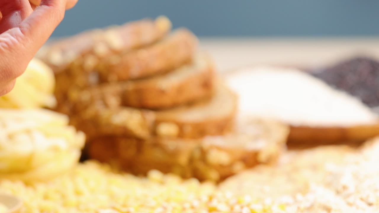 Hands break a cookie against a backdrop of various grains under bright lighting, highlighting texture and detail