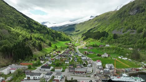 Eidsdal-town-in-More-and-Romsdal-with-beautiful-valley-background-and-ferry-alongside-in-front---Forward-moving-aerial-with-beautiful-patches-of-sunlight-during-spring