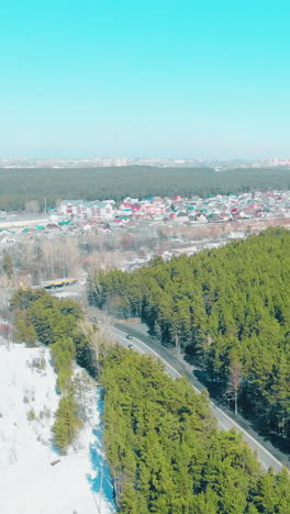 beautiful vast green pine tree forest crossed by busy highway borders by large city under blue sky bird eye view