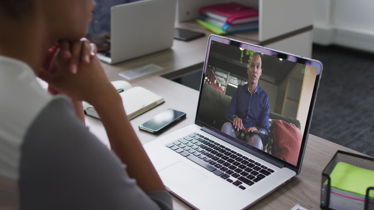 Mid section of african american woman having a video call with male colleague on laptop at office