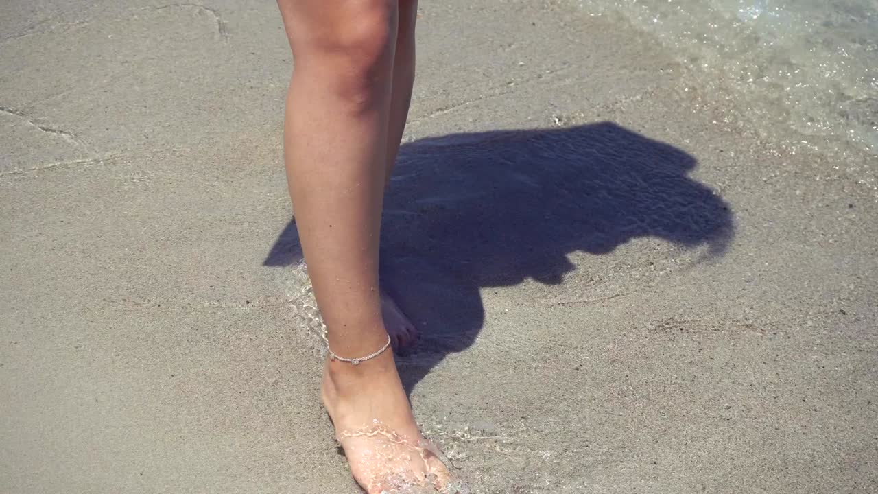 Giovane donna che cammina sulla sabbia bagnata in spiaggia 4k