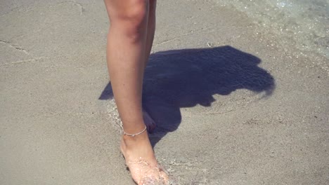 una mujer joven caminando sobre la arena húmeda en la playa 4k