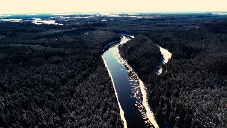 un río sinuoso cerca de un pequeño pueblo con un macizo forestal