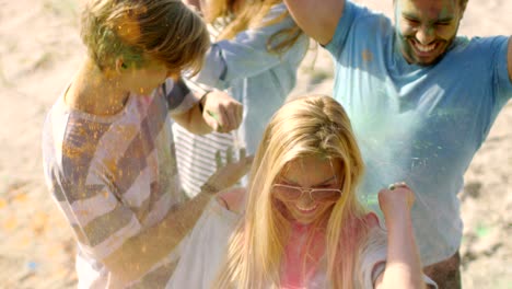 high angle shot of multi-ethnic group of diverse young people dancing and throwing colorful powder in the air and raising hands in celebration of holi festival. they have enormous fun on this sunny day.