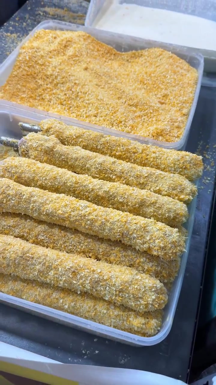 Chef Coating Skewered Food in Breadcrumbs for Deep Frying