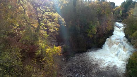 Imágenes-De-Drones-Girando-Lentamente-De-Una-Cascada-En-Un-Desfiladero-Rodeado-De-árboles-Coloridos-En-Otoño