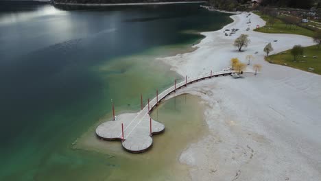 vista tranquila de un pequeño puente de madera en la orilla del lago molveno en trentino, italia