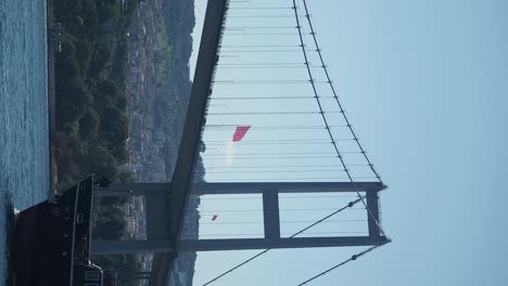 bosphorus bridge with turkish flag and ship on a sunny day