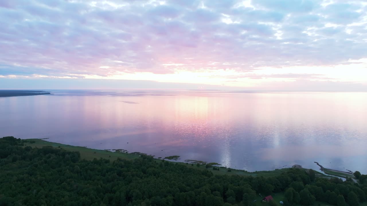 Flying in sunset over a calm and tranquil coastline and sea with magical light reflecting from the water