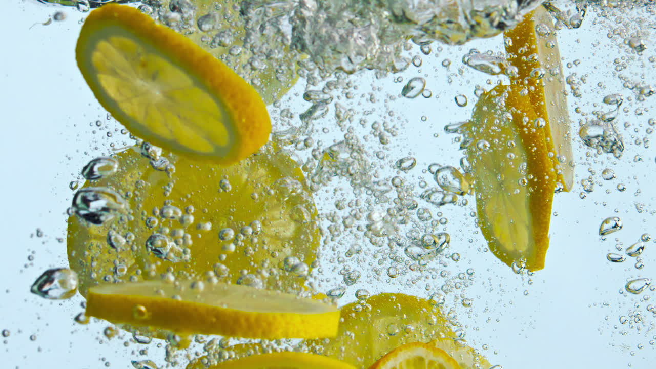 Sliced orange fall water in super slow motion close up. Citrus pieces floating.