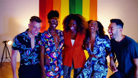 joyful diverse group laughing together in front of a rainbow pride flag
