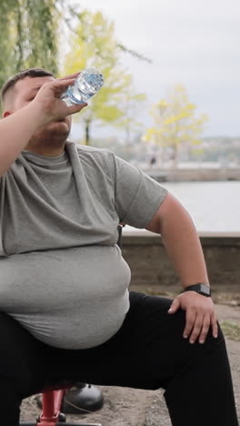 overweight man drinks water while exercising outdoors weight loss concept overweight man drinks water while exercising outdoors weight loss concept