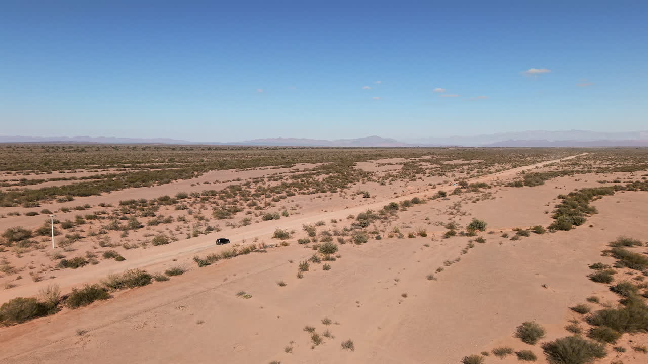 Aerial view of cars crossing on a dusty road through the vast Argentine desert in South America
