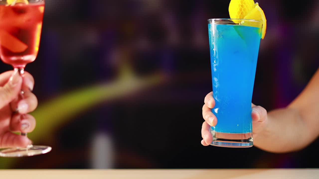 Two vibrant cocktails clink in a lively bar setting, highlighting colorful drinks and festive atmosphere with dynamic lighting