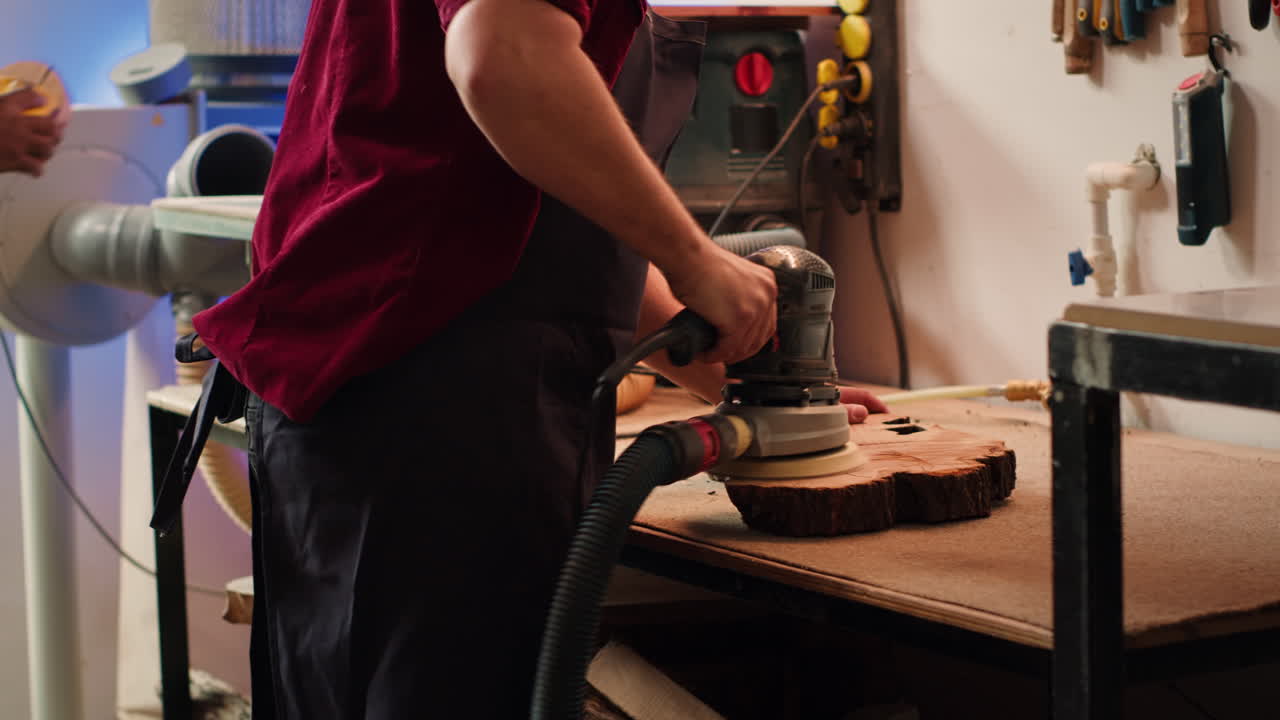 Woodworking expert in carpentry shop using angle grinder to fix wooden surface