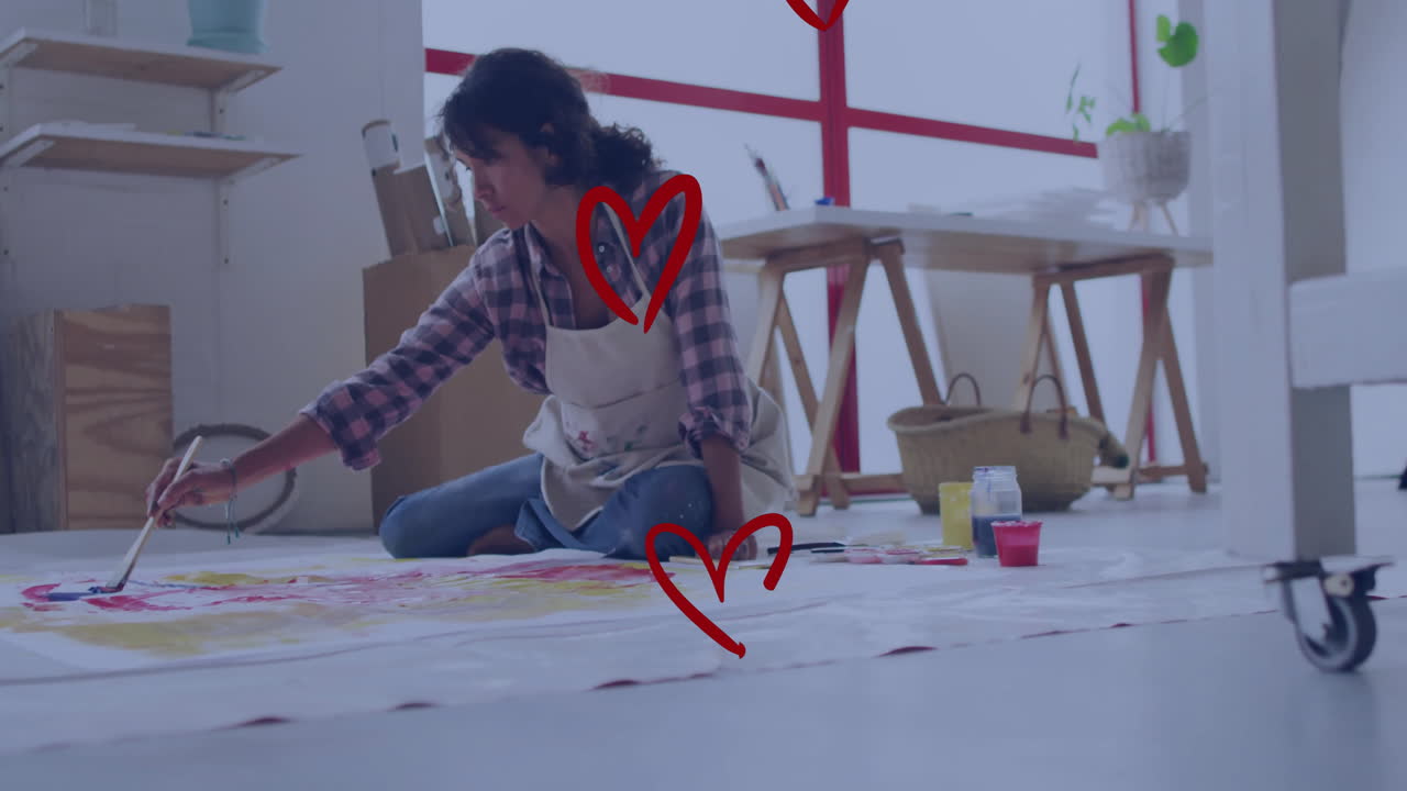 Artist painting on large canvas with red heart animations around