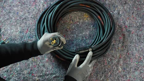 electrician with gloves on checking if the newly made rolled up electric plug is perfect to sell