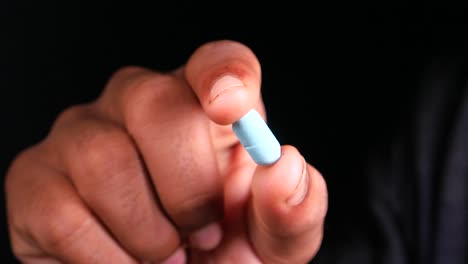 person holding a light blue pill