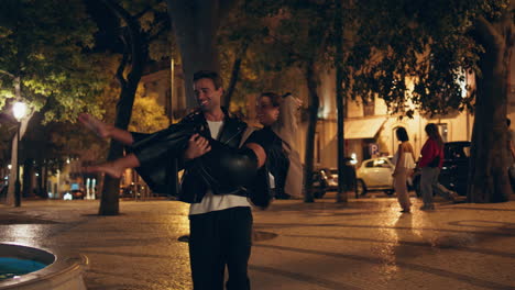 novio cariñoso girando mujer en los brazos por la noche. feliz gente alegre