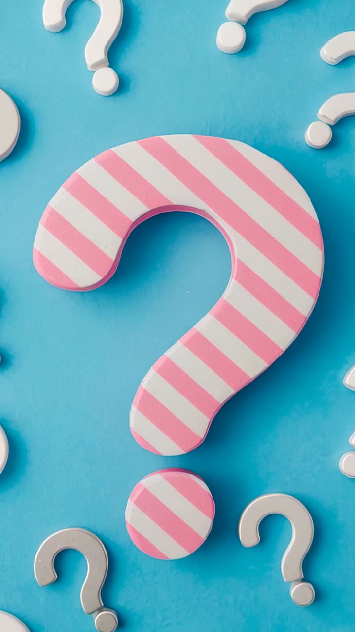 Video verticale: visualizzazione di un punto interrogativo rosa-bianco su una superficie blu con punti interrogativi argentati
