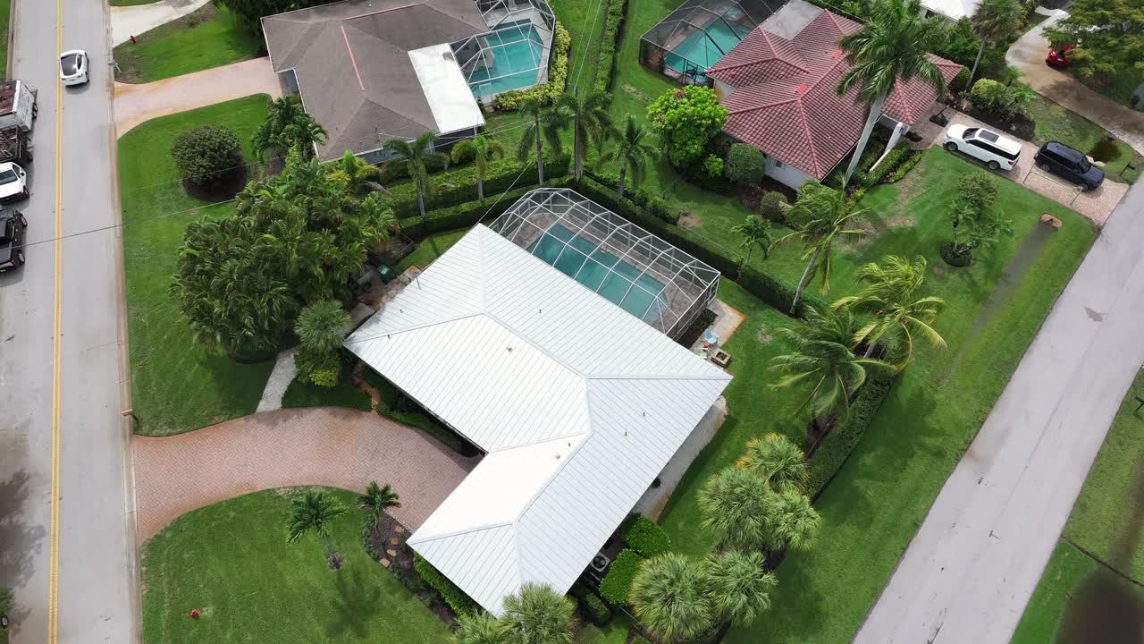 Aerial top down of luxury villas with swimming pool during sunny day in Florida, USA. Car driving on street. Growing palm trees decorating yard.