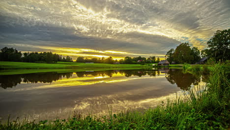 clouds pass like a blanket in the sky over a large lake with a house on the shore