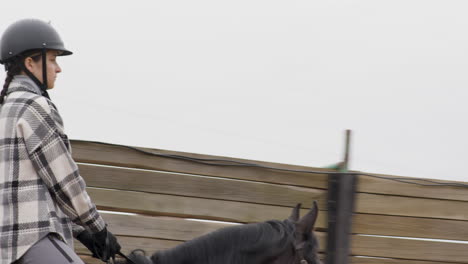 teenager riding black horse outside the stables