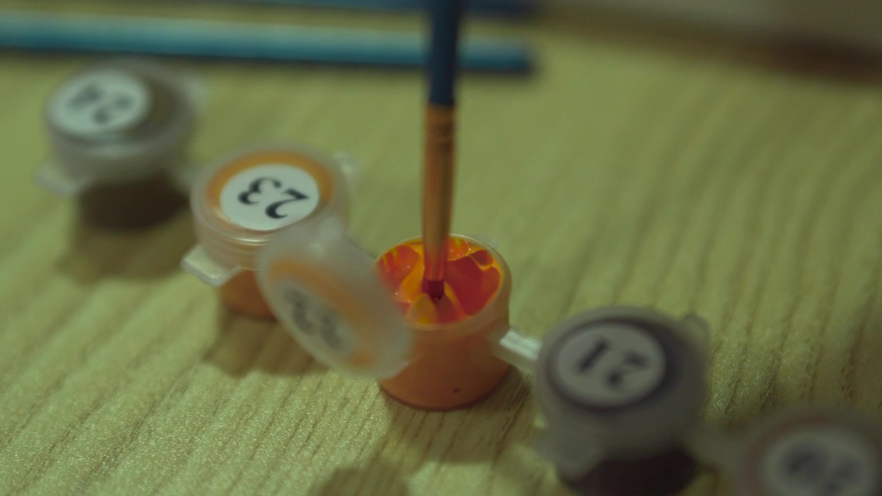Close up of paint brush dipping into coloured paint pot
