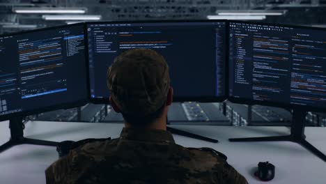 back view of tired asian military stretching while write code with multiple computer screens in data center