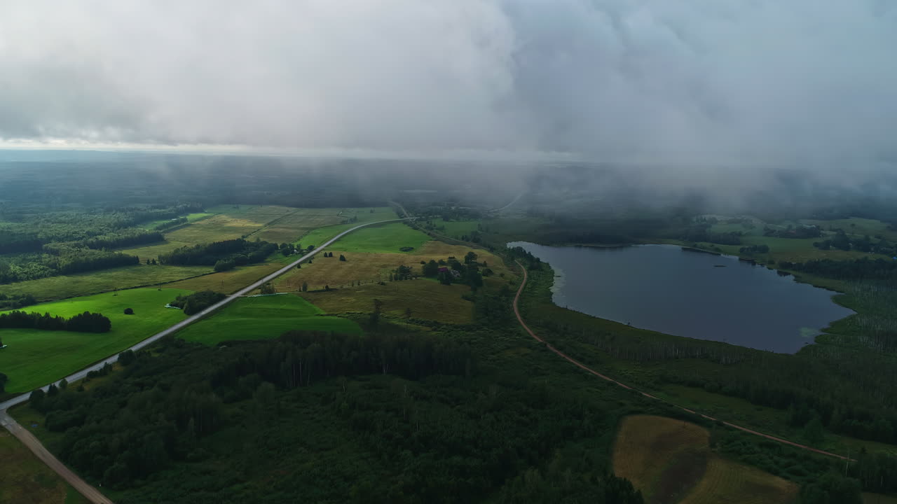 nubes bajas y niebla llenan el aire sobre un lago rodeado de un campo verdoso