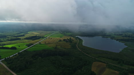 Niedrige-Wolken-Und-Nebel-Füllen-Die-Luft-über-Einem-See,-Umgeben-Von-Grüner-Landschaft