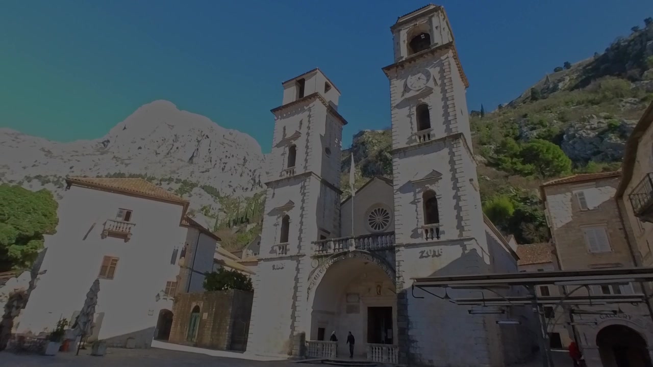 Ripresa dal basso della facciata e dei campanili della storica Cattedrale di San Trifone con sfondo montuoso nel centro storico di Cattaro, Montenegro.