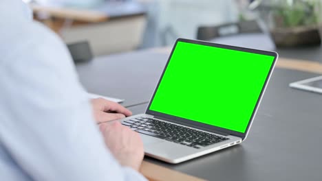 hombre con gafas usando una computadora portátil con pantalla cromada
