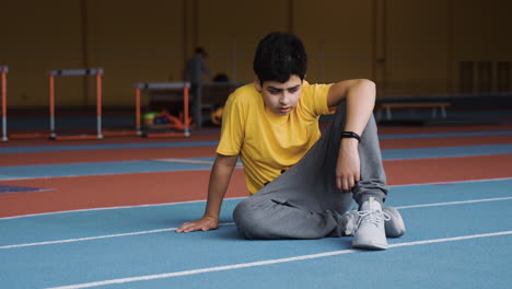 Niño-Descansando-En-Pista-De-Atletismo