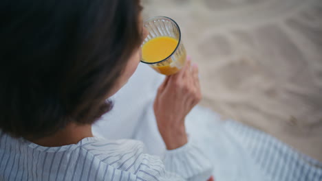 hand holding juice glass closeup. top view woman drink organic orange beverage