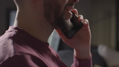 primer plano de un joven complacido en casa que recibe una llamada telefónica que confirma la oferta de trabajo