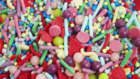 vibrant sprinkles cascade onto a surface, creating a colorful, textured pattern in a close-up, slow-motion view