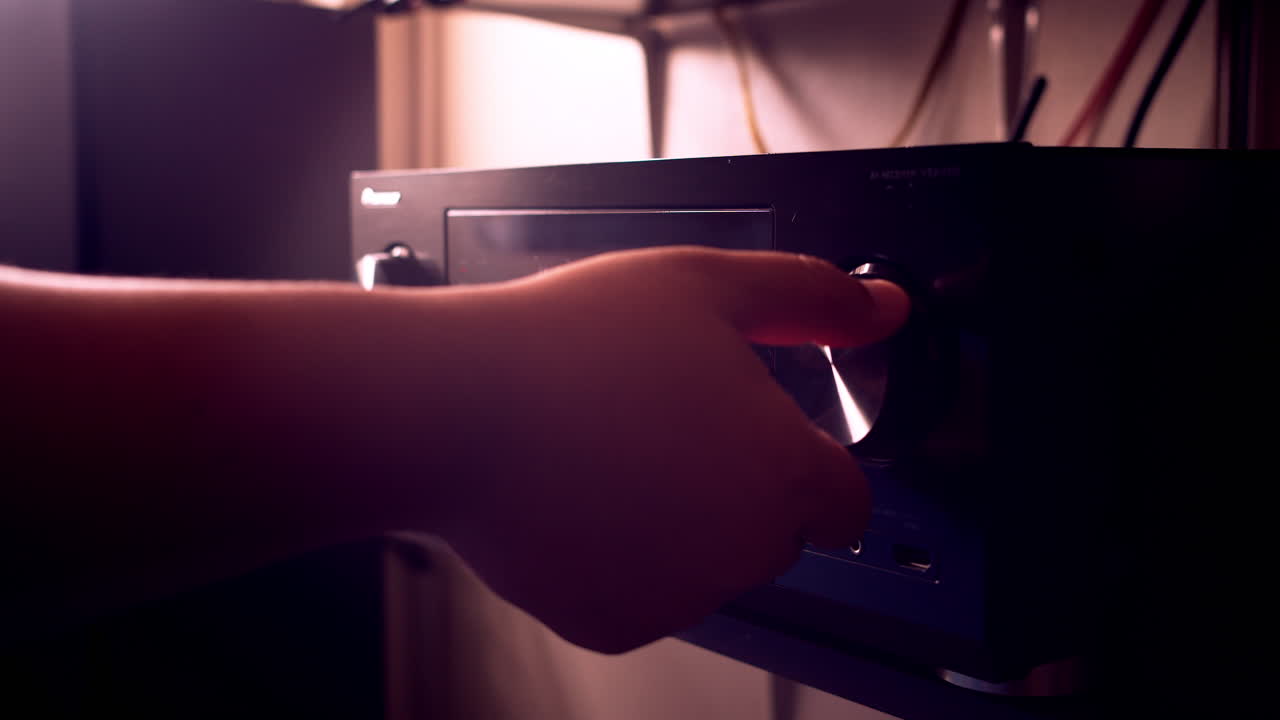 Mano che regola il volume dell'amplificatore per un suono immersivo con il nostro moderno home theater.