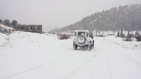 land rover defender d90 driving through snowy back country road in alpine rocky mountains valley near nederland boulder colorado