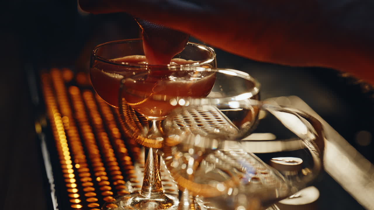 Mani che versano un cocktail alcolico in bicchieri su un bancone da bar, primo piano