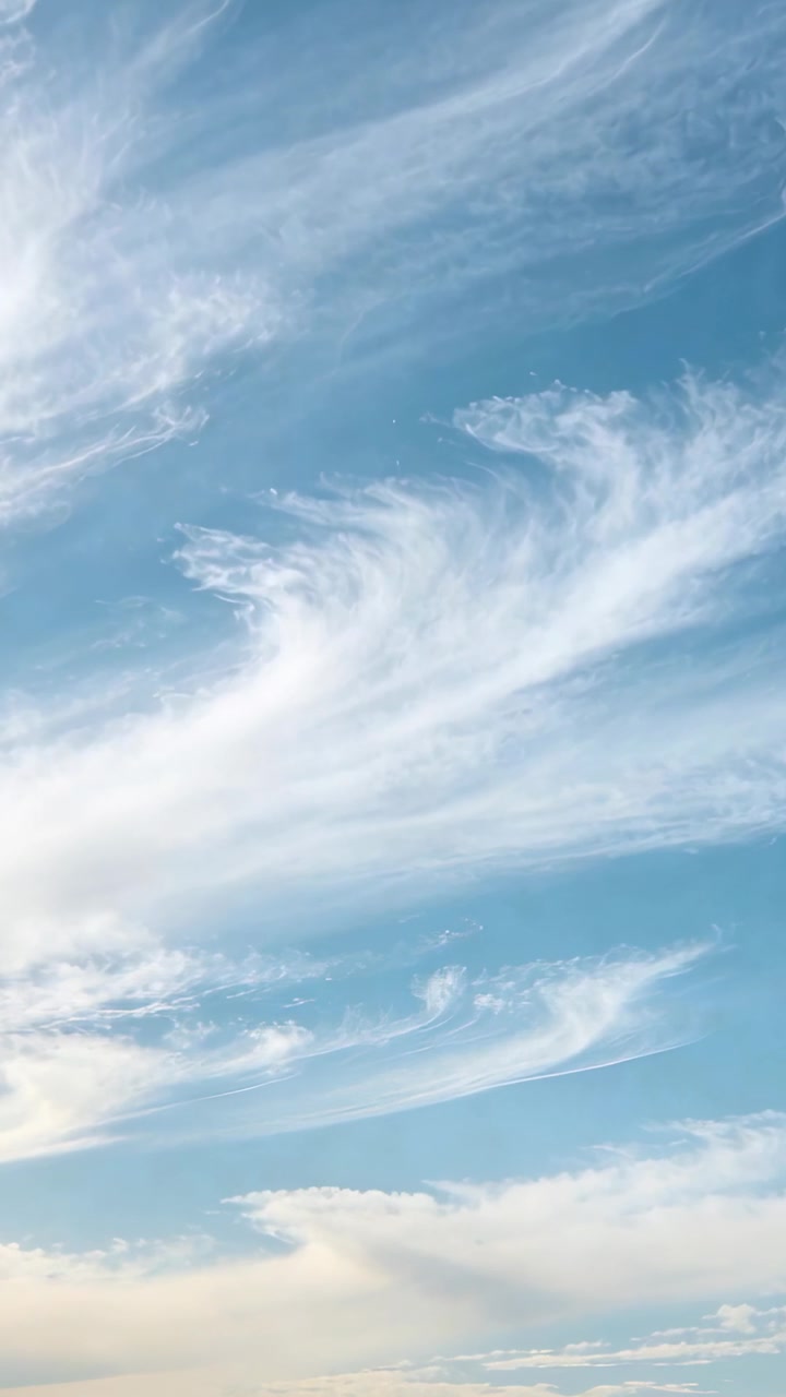 Blå himmel med cirrusskyer driver langsomt og omformes under mild øvre vind til vejrstudie.