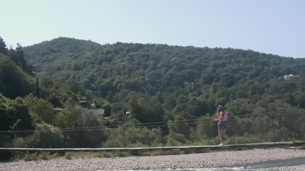 산악 지형 의 다리 를 가로질러 고 있는 소녀