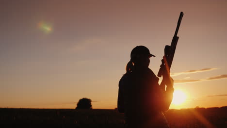 una mujer con un arma cruza el campo al comienzo de la temporada de caza disparo de steadicam