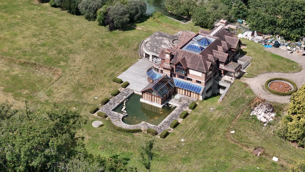 Establishing aerial view across unfinished celebrity mansion and rundown private gardens